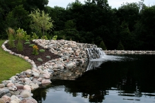 Small waterfall going from rock wall and into pond