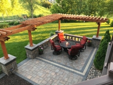 Square stone patio with tabletop fire pit and pergola