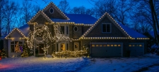 Front yard of house with trees and bushes covered in lights